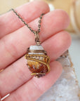 Raw citrine pendant held in hand showing size wire wrapped in antique bronze copper unisex necklace
