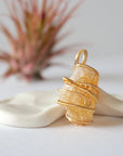 Side angle view of raw citrine pendant showing crystal dimension and wire wrapping detail - natural unpolished stone in gold plated copper handmade jewelry