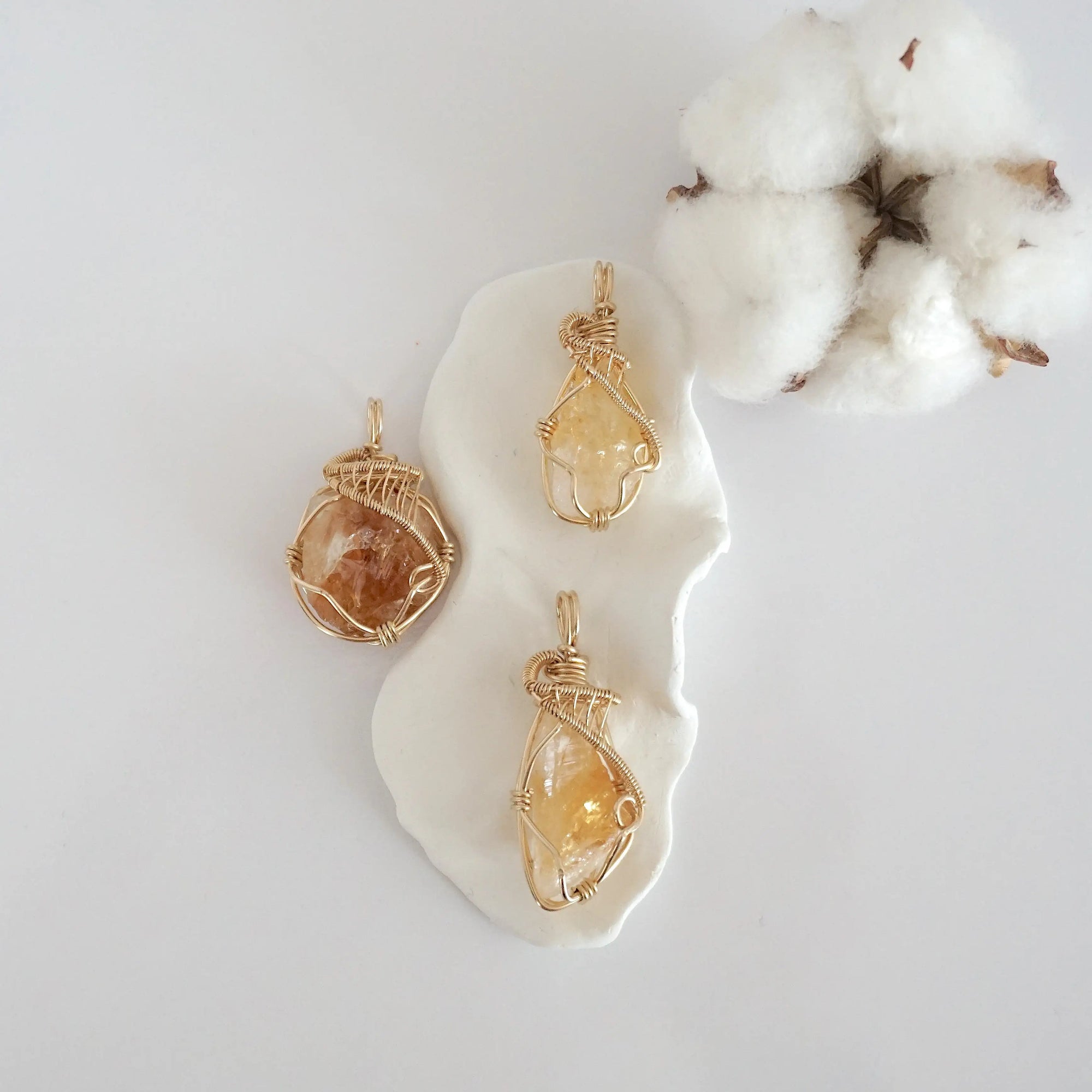 Three raw citrine pendants in 14k gold filled, showing natural variation in size, shape, and color. Handcrafted November birthstone jewelry by Designs by Nature Gems.