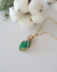 Raw emerald necklace in 14k gold filled laying flat. Handcrafted May birthstone jewelry for women by Designs by Nature Gems.