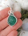 Raw emerald necklace for women shown in hand for size reference with natural emerald pendant in 925 sterling silver wire wrapping