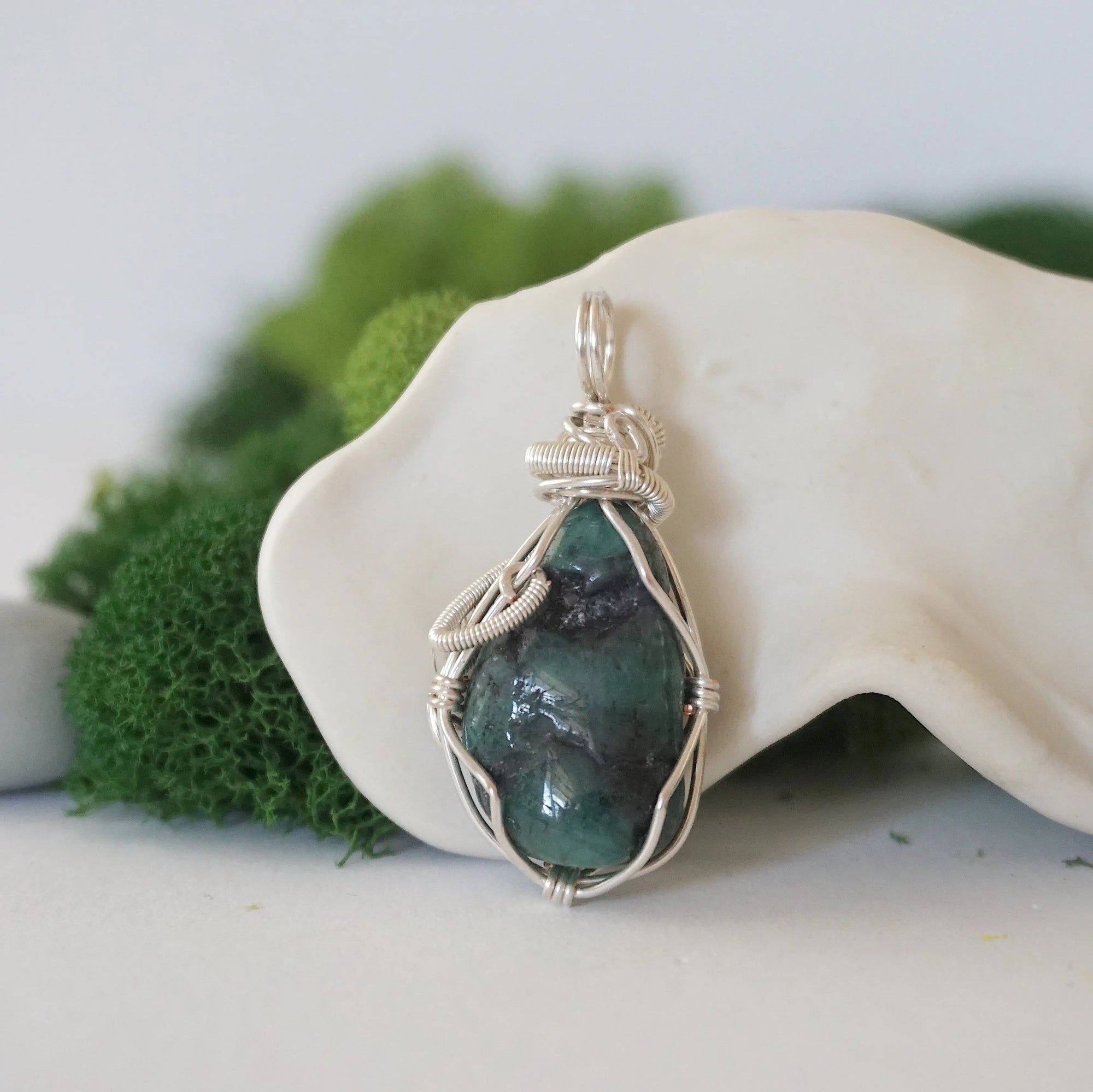 Back view of raw emerald pendant showing detailed artisan wire wrapping in soft silver copper.
