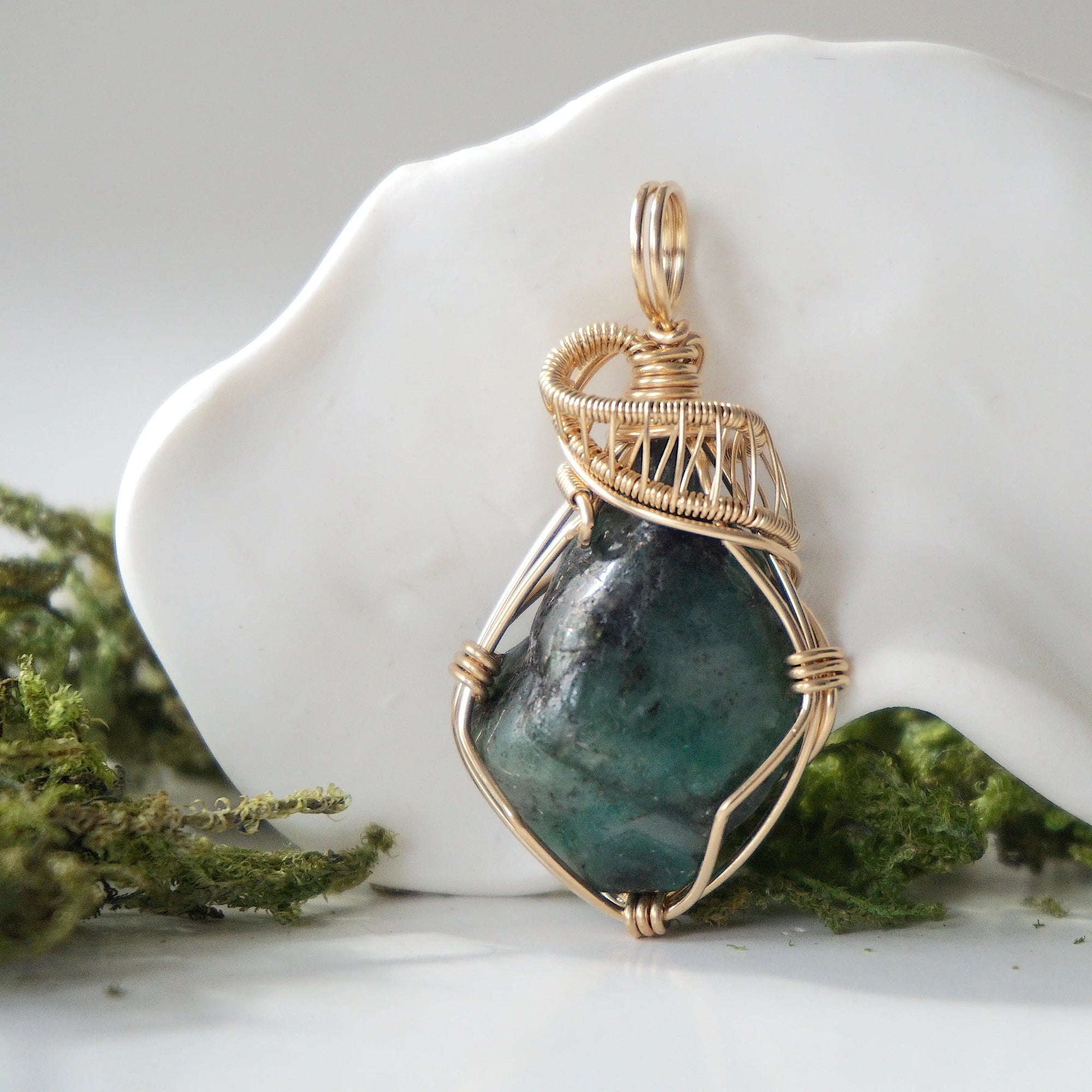 Front view of natural polished-raw emerald pendant with detailed artisan wire wrapping in 14k gold-filled wire.