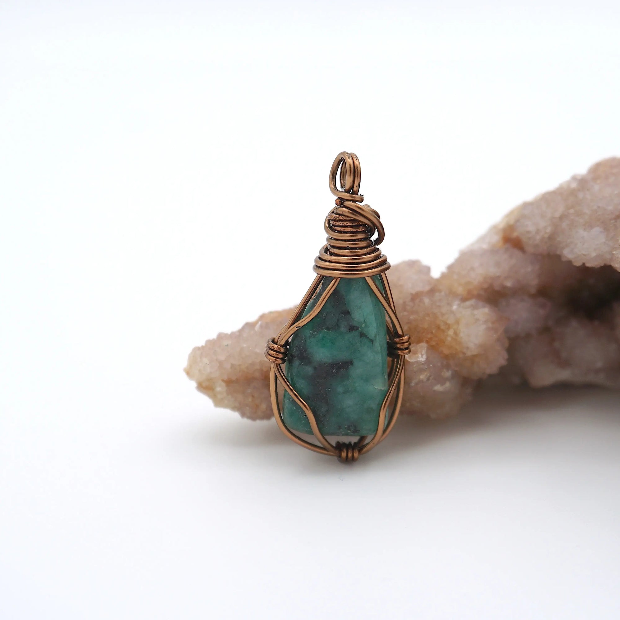 Front view of natural polished-raw emerald pendant with simple artisan wire wrapping in antique bronze copper.