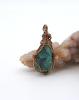 Front view of natural polished-raw emerald pendant with simple artisan wire wrapping in antique bronze copper.