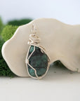 Right angle view of raw emerald pendant showing detailed handcrafted wire wrapping in soft silver copper.