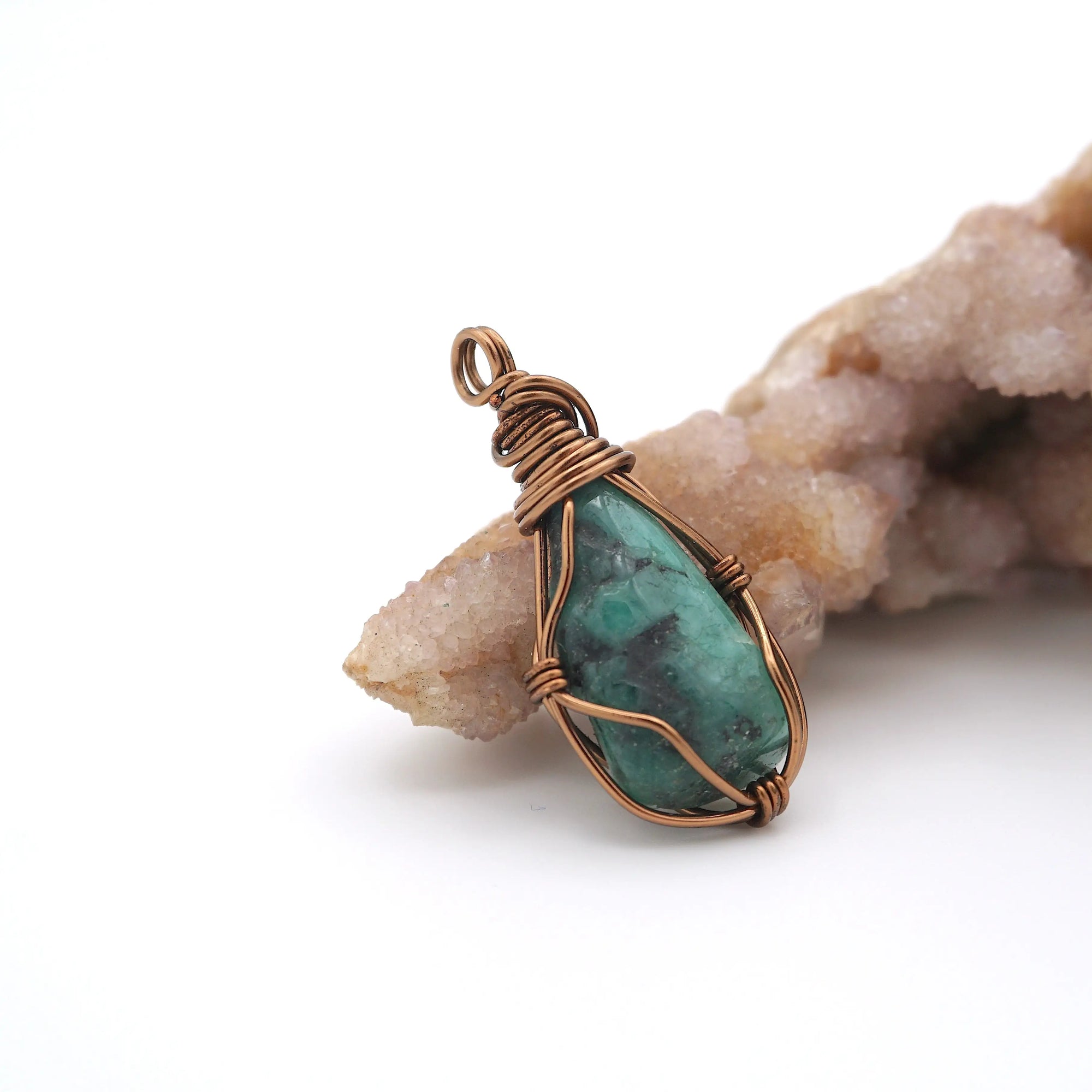 Right angle view of raw emerald pendant showing handcrafted antique bronze copper wire wrapping detail.