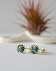 Raw emerald stud earrings in 14k gold vermeil at a slight angle showing natural green emerald and minimalist prong setting