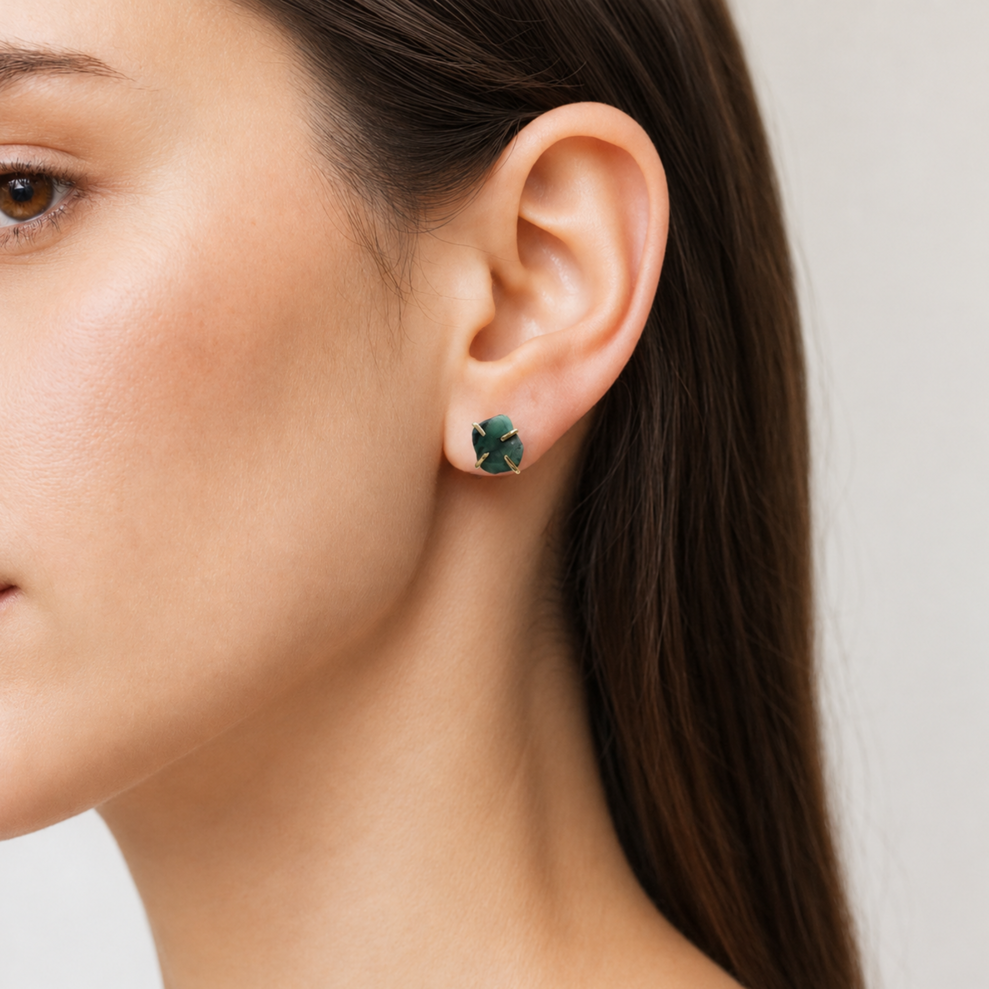 Female model wearing raw emerald stud earrings in 14k gold vermeil with natural emerald stones and minimalist design