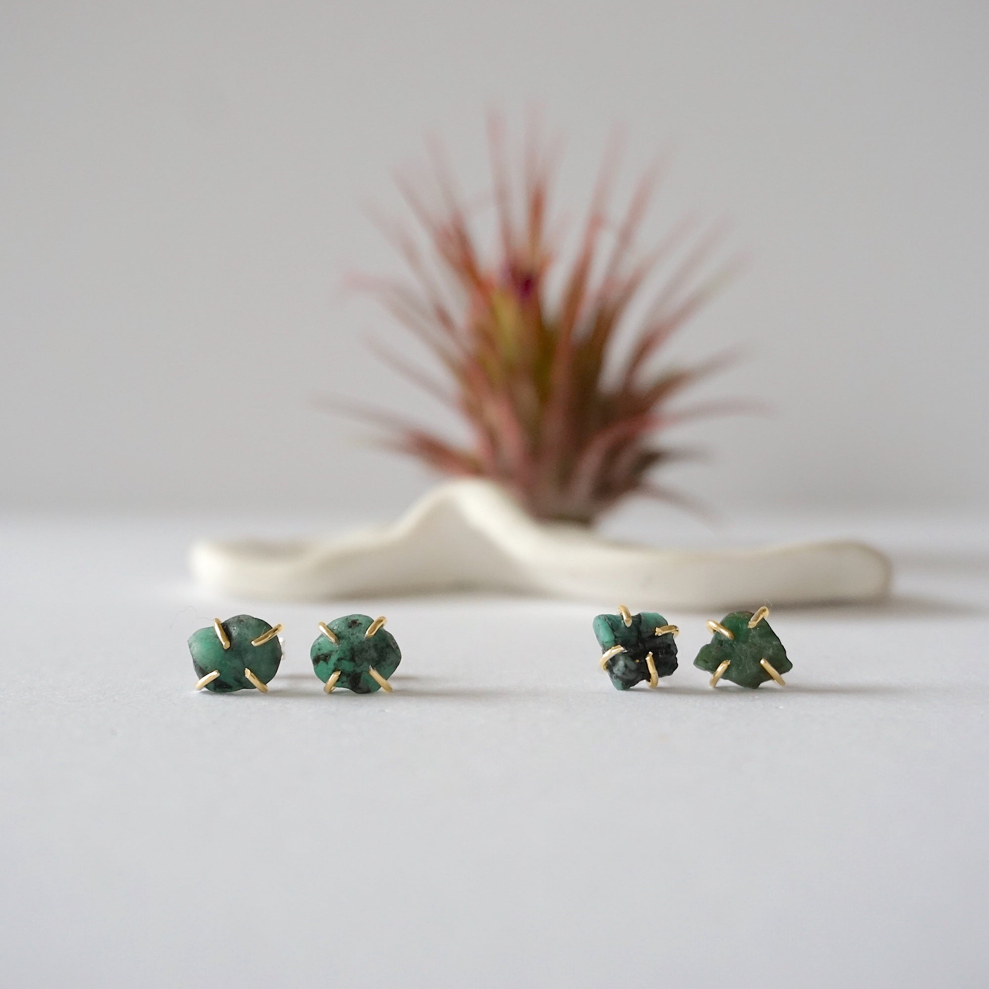 Two pairs of raw emerald stud earrings in 14k gold vermeil showing natural variation in emerald shape size and green colour