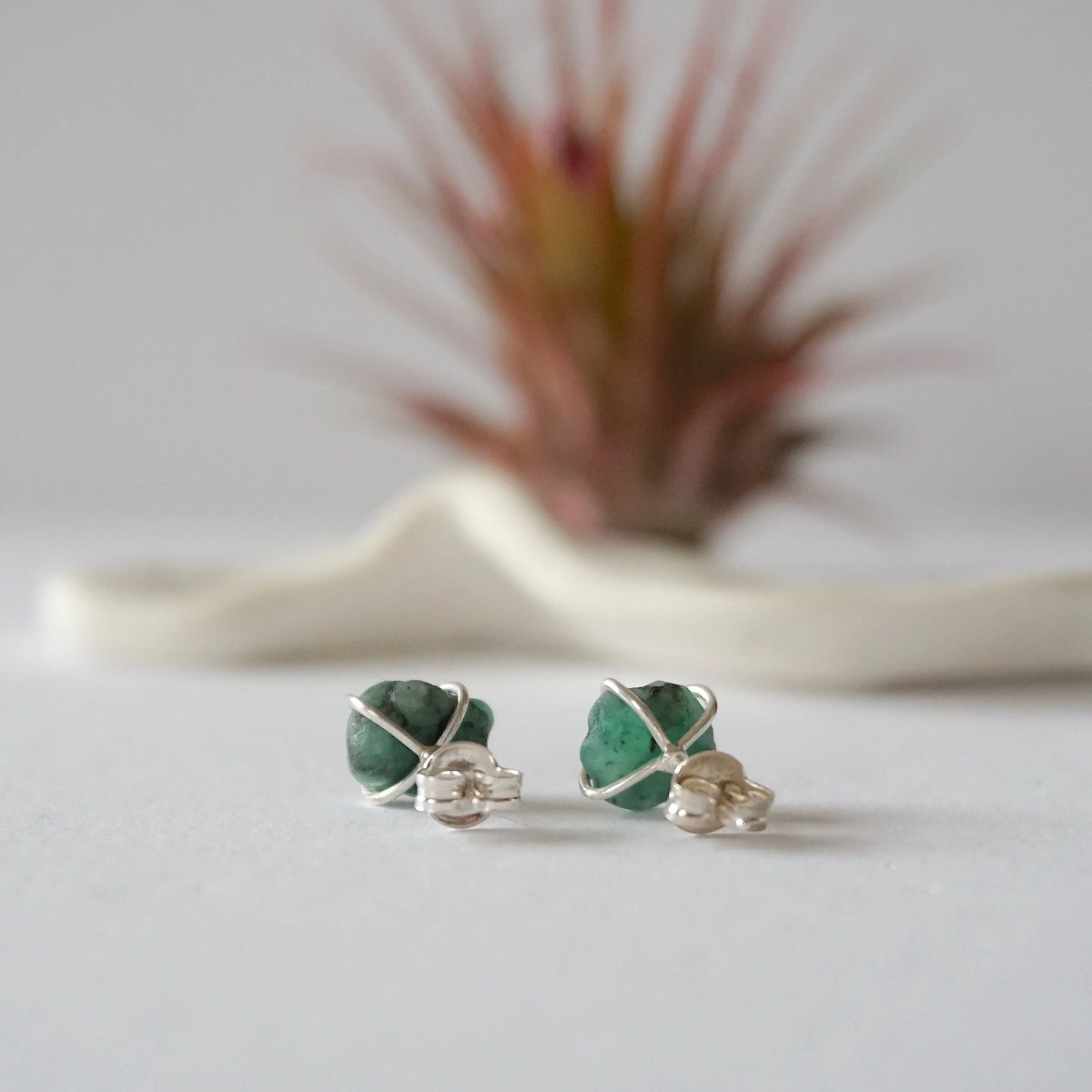 Back view of raw emerald stud earrings in sterling silver showing artisan setting and earring post detail