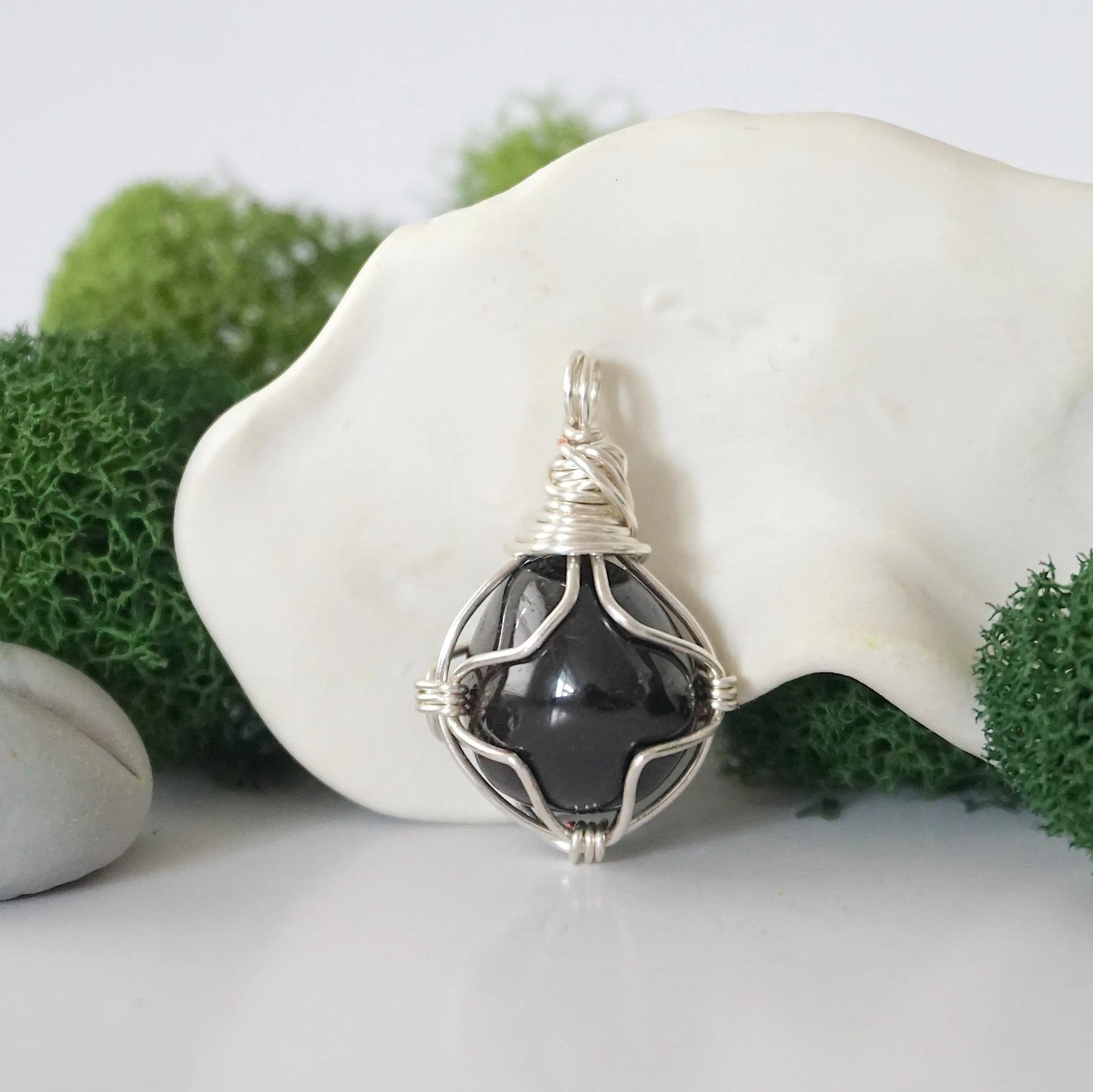 Detailed front angle view of simple raw garnet pendant in silver wire