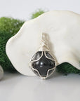 Detailed front angle view of simple raw garnet pendant in silver wire