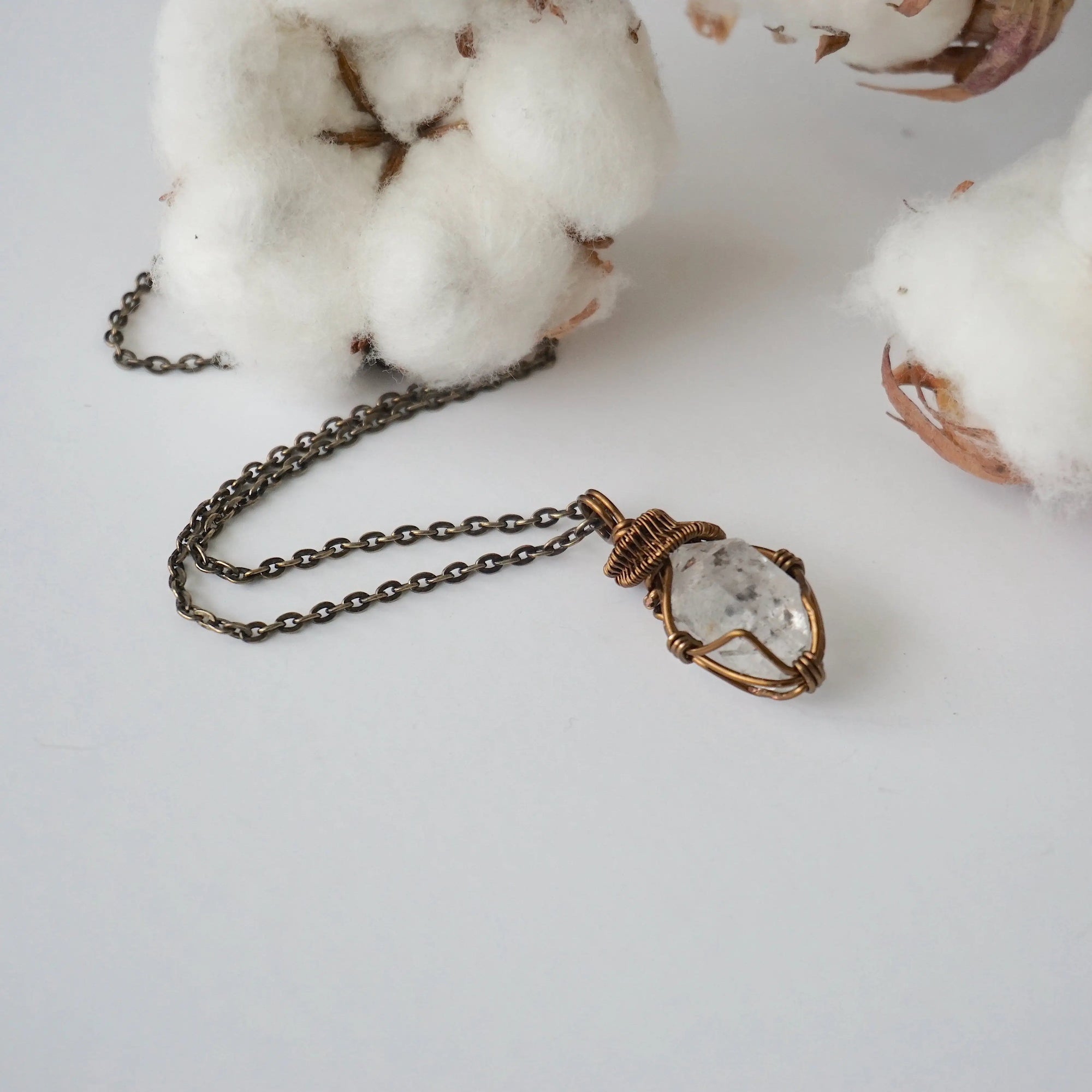 Detailed view of raw Herkimer diamond pendant on antique bronze chain for women with handmade artisan wrapping.