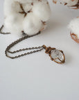Detailed view of raw Herkimer diamond pendant on antique bronze chain for women with handmade artisan wrapping.