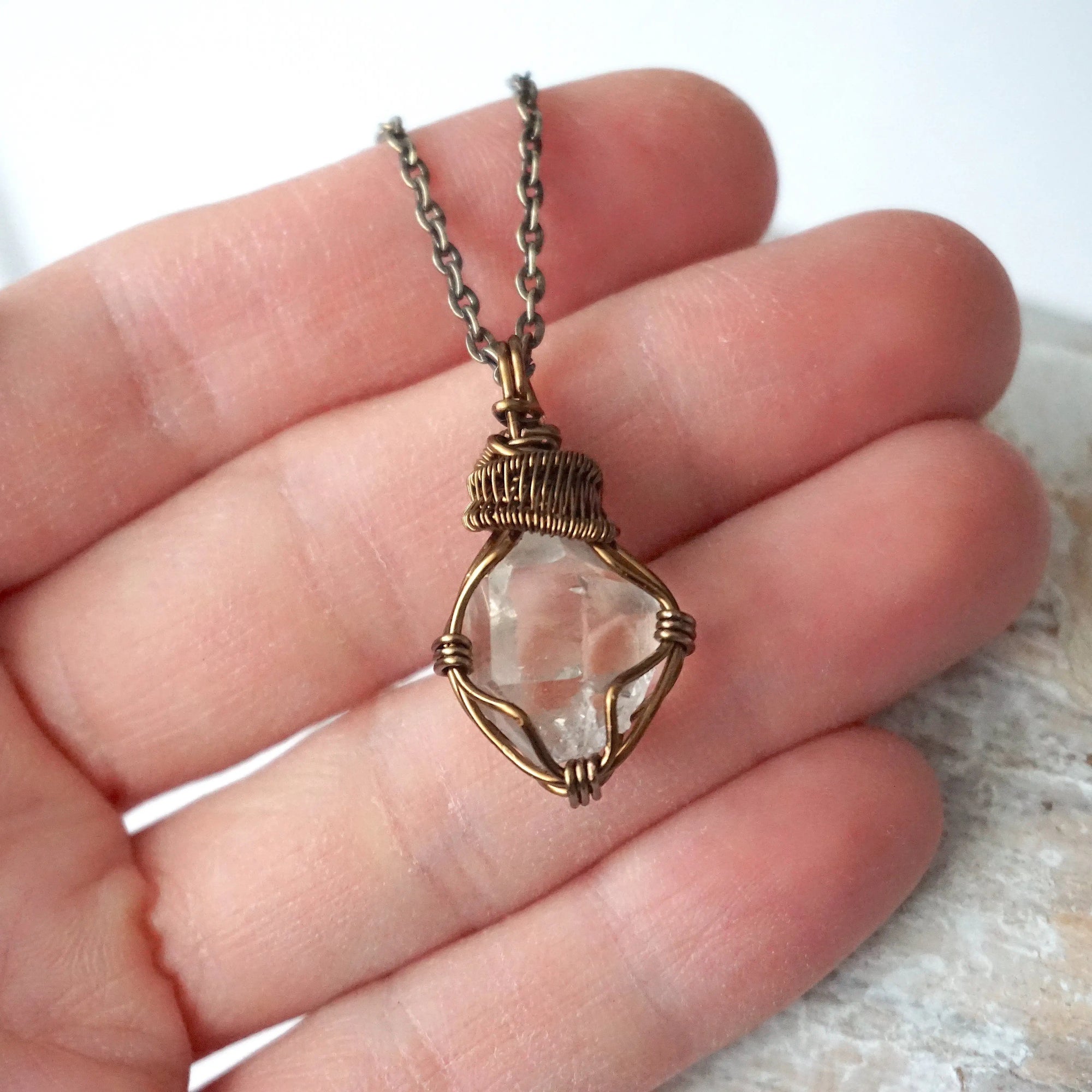 Raw Herkimer diamond necklace for women shown in hand for size reference with antique bronze copper wire wrapping.