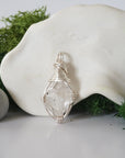 Detailed front angle view of simple raw Herkimer diamond pendant in silver wire