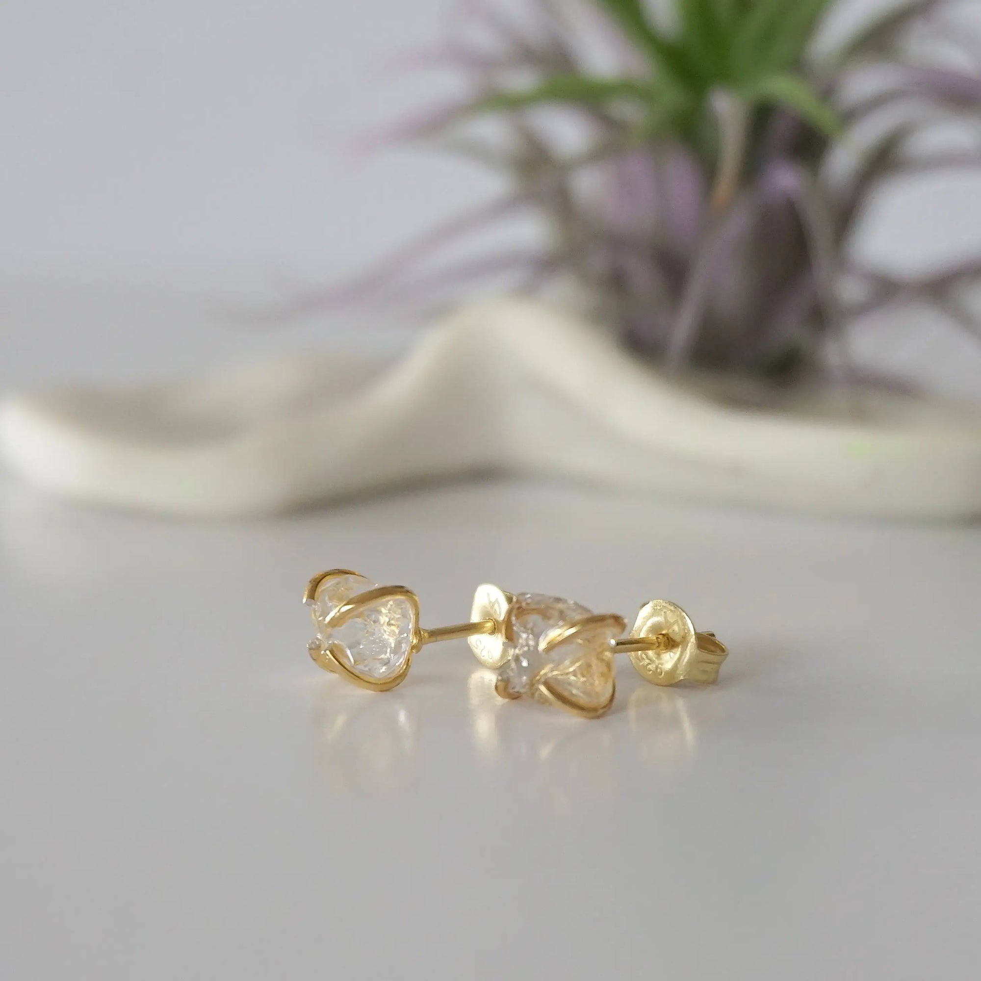 Left side angle view of raw Herkimer diamond stud earrings showing 14k gold vermeil prong setting detail.