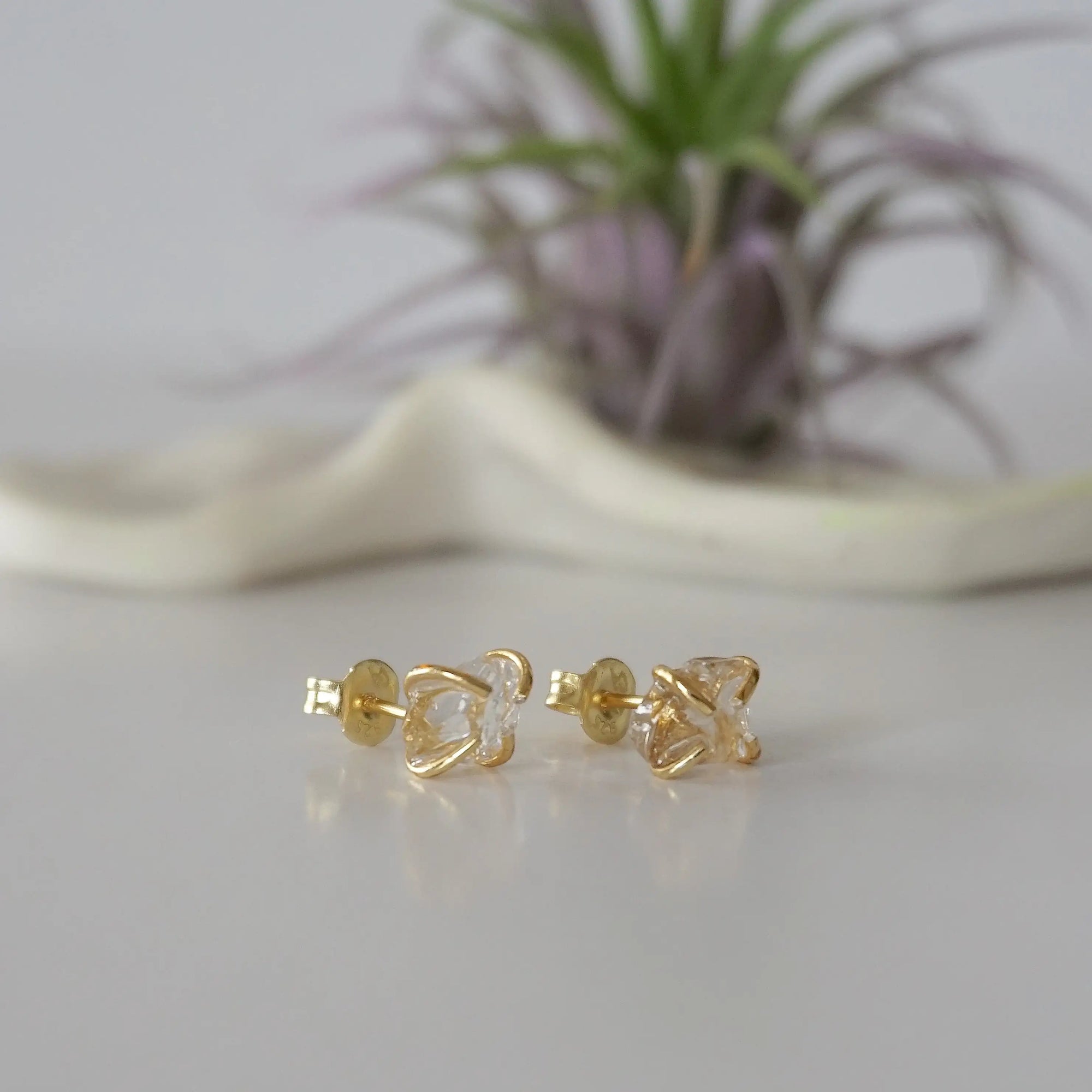 Right side angle view of raw Herkimer diamond stud earrings highlighting 14k gold vermeil prong setting.