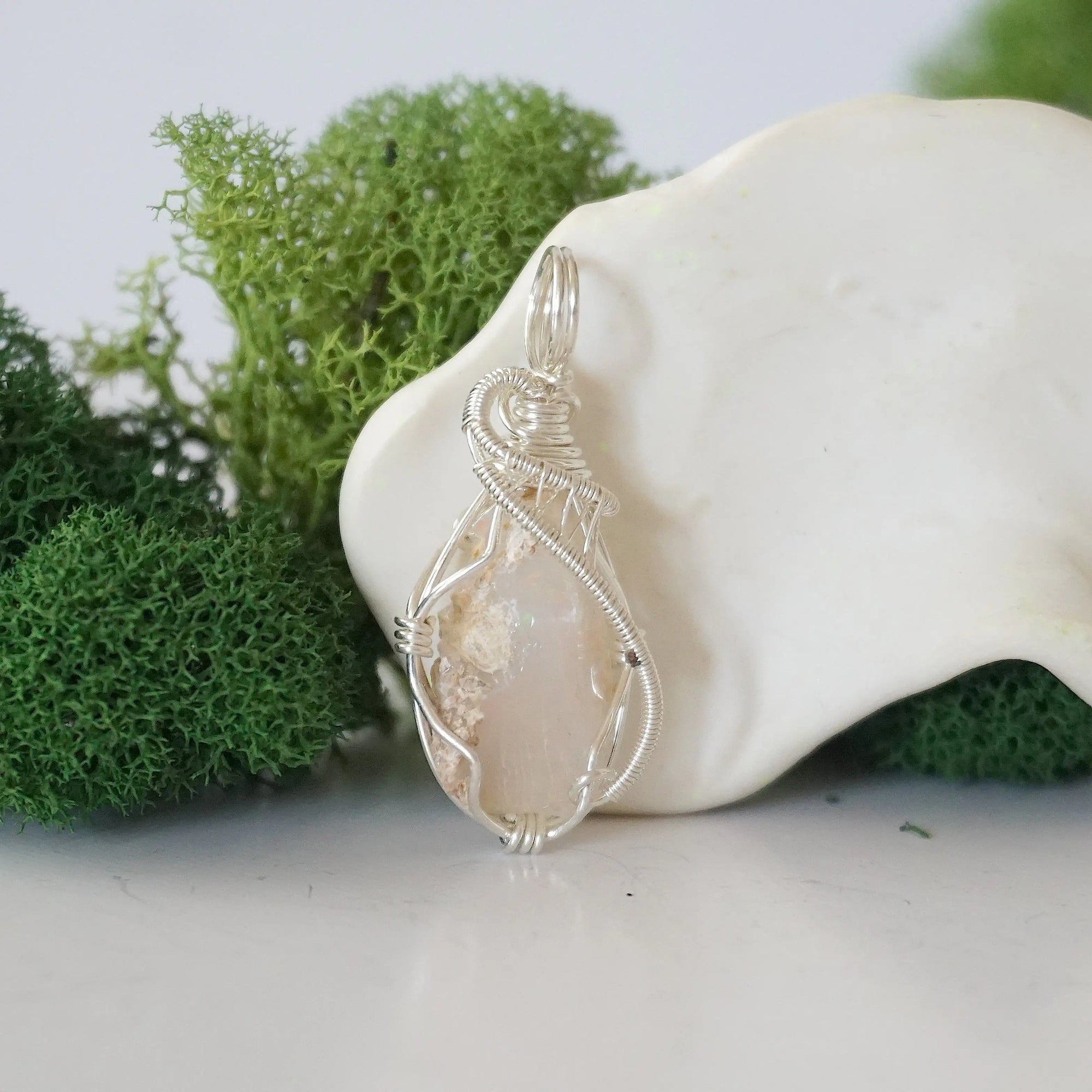 Front view of raw Ethiopian opal pendant — natural unpolished opal stone with colour play, hand-wrapped in detailed 925 sterling silver wire, handcrafted artisan jewelry