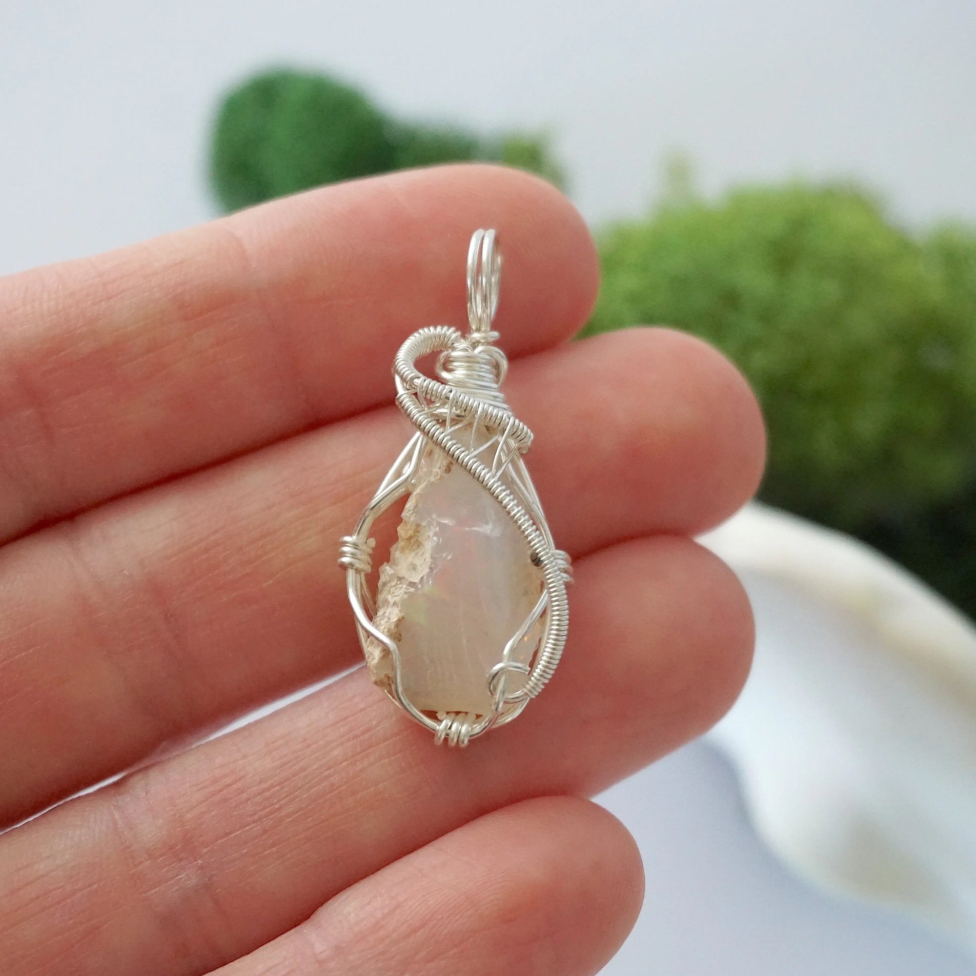 Handmade raw Ethiopian opal pendant held in hand showing size — natural opal stone wire wrapped in 925 sterling silver, 7-10 carats, one of a kind