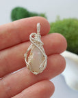 Handmade raw Ethiopian opal pendant held in hand showing size — natural opal stone wire wrapped in 925 sterling silver, 7-10 carats, one of a kind