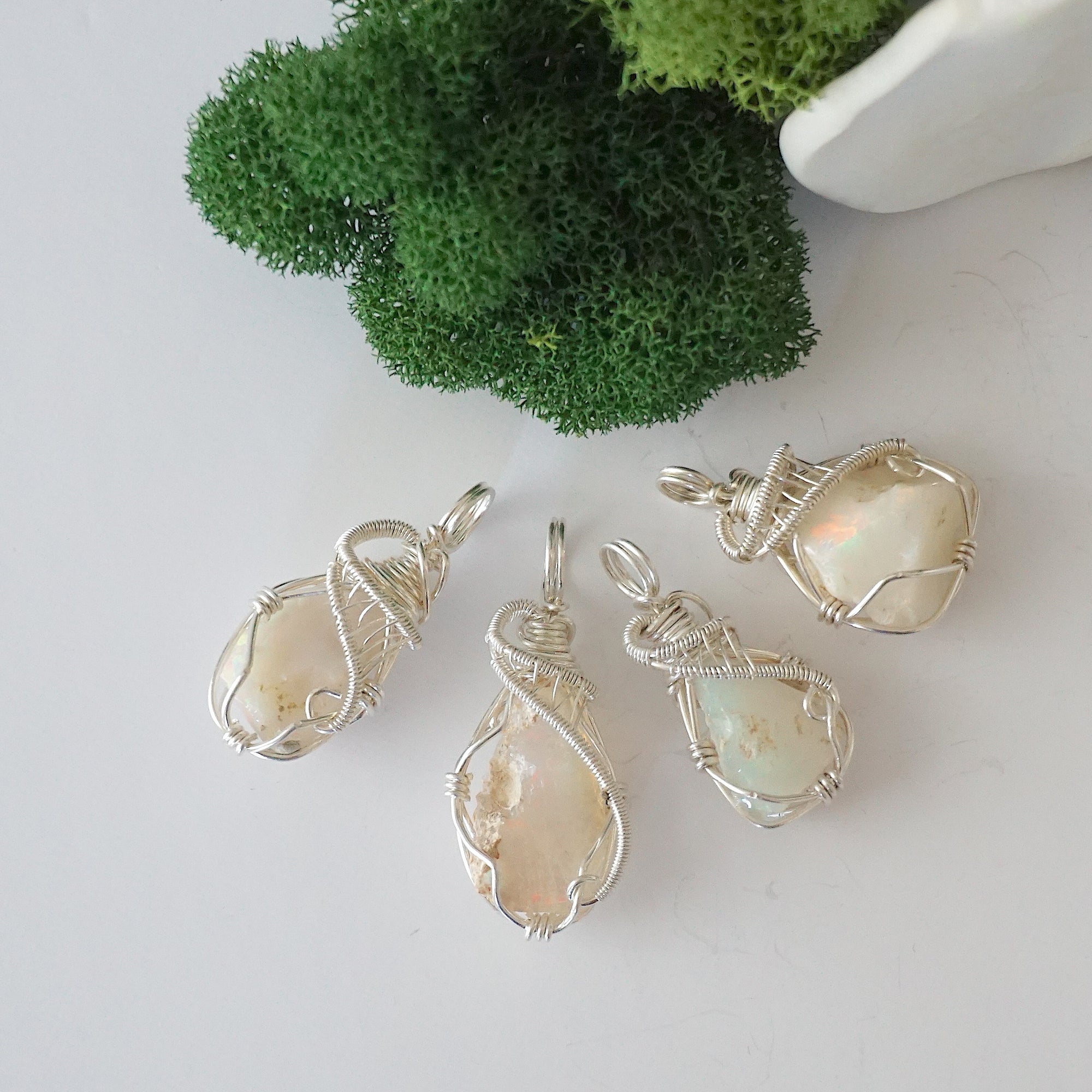 Four raw Ethiopian opal pendants showing natural variation in stone size, shape, and colour play — each one of a kind, October birthstone, 925 sterling silver wire wrapped, Designs by Nature Gems