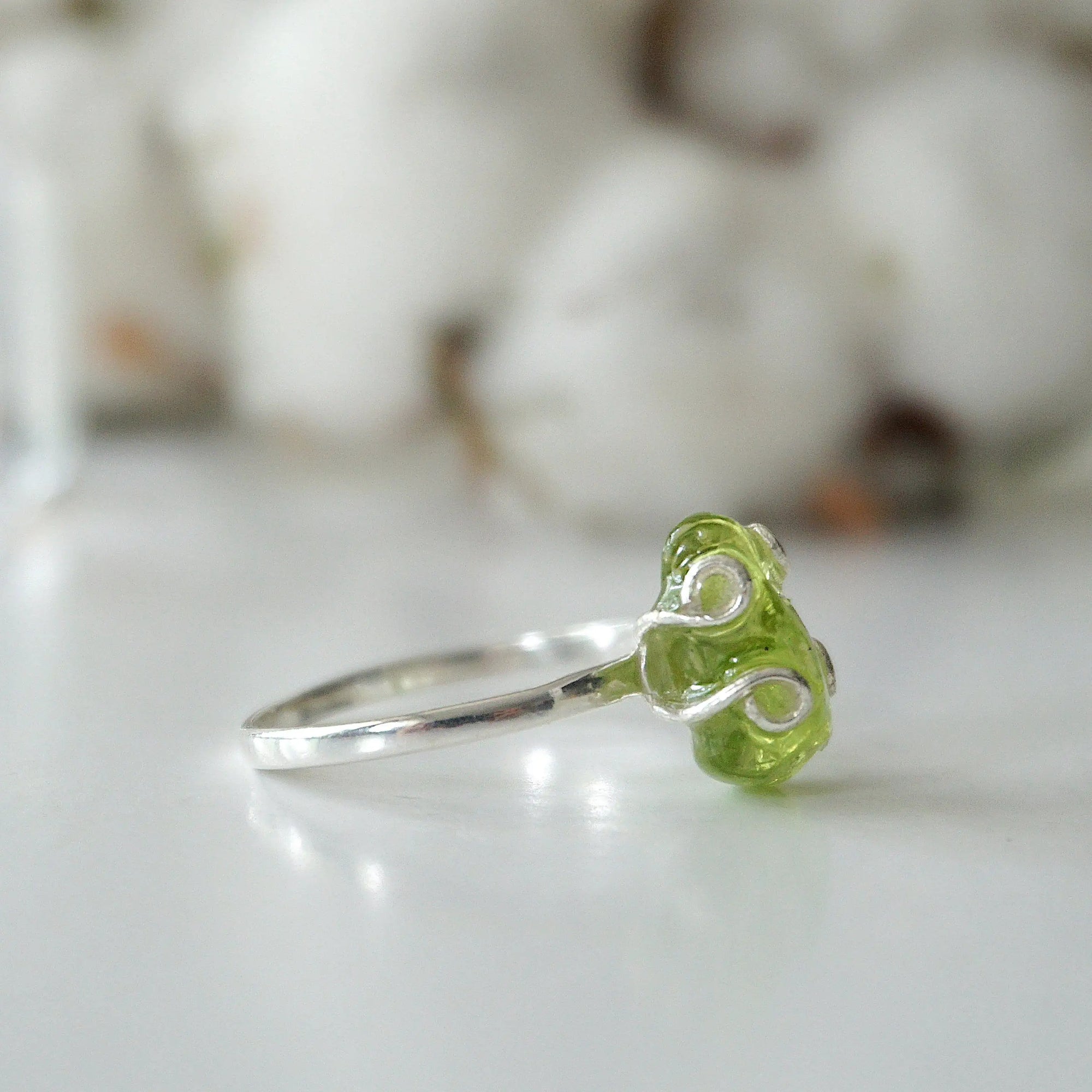 Left side angle of raw peridot adjustable ring — 925 sterling silver artisan wire setting and smooth band detail, handcrafted August birthstone crystal ring for women