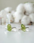 Two raw peridot adjustable rings showing natural variation in stone size, shape, and olive green colour — handcrafted 925 sterling silver August birthstone crystal rings for women