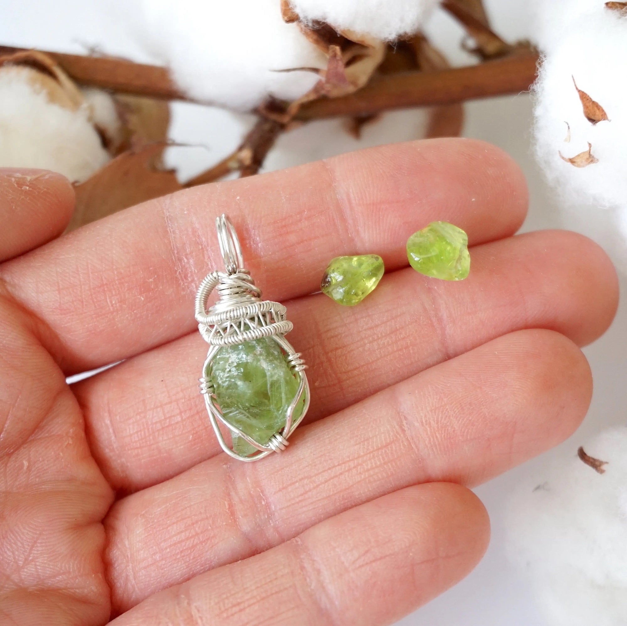 Raw peridot jewelry set for women held in hand — vivid lime green crystal pendant and stud earrings in 925 sterling silver, handmade August birthstone set by Designs by Nature Gems