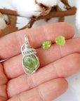 Raw peridot jewelry set for women held in hand — vivid lime green crystal pendant and stud earrings in 925 sterling silver, handmade August birthstone set by Designs by Nature Gems