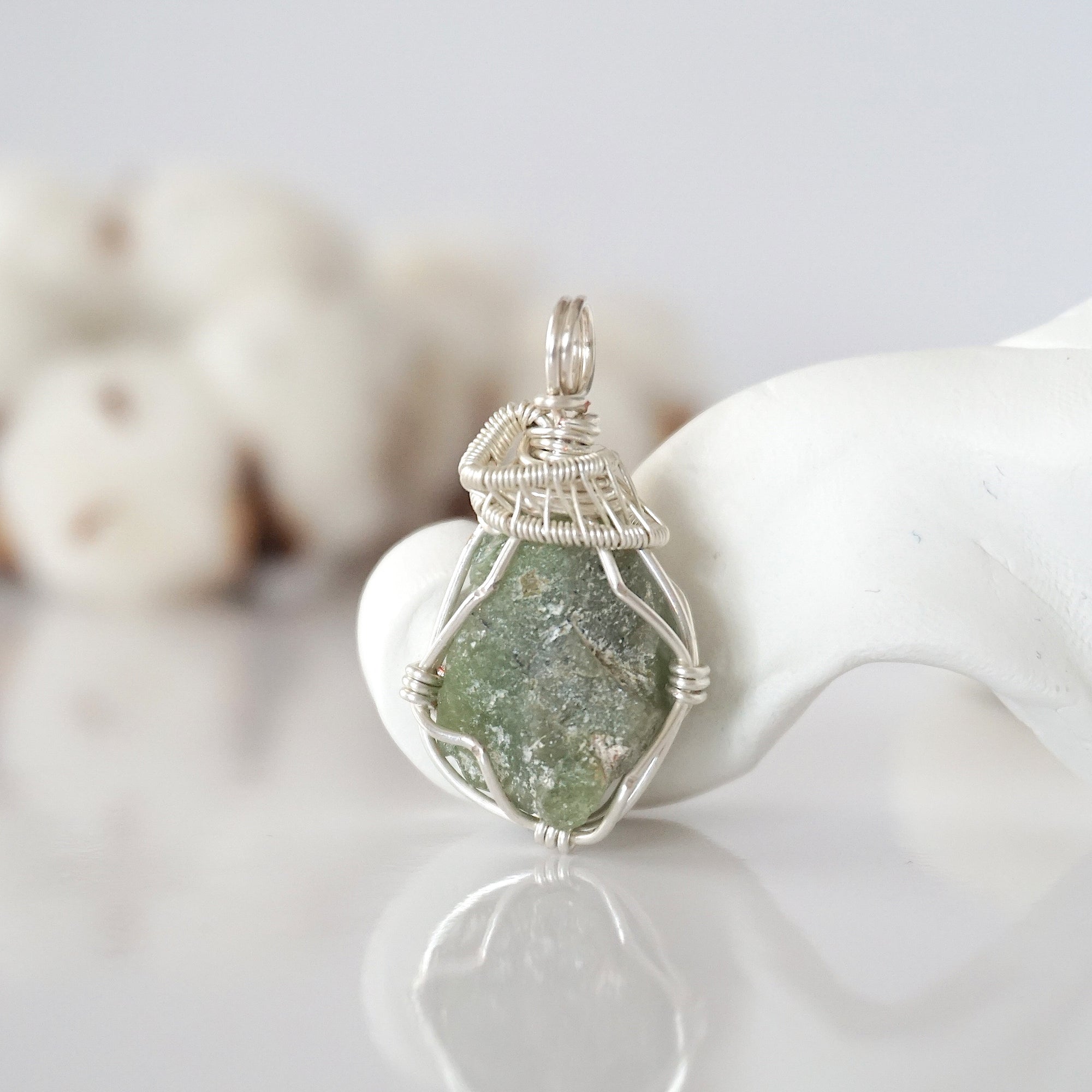 Front view of raw peridot pendant — natural unpolished green peridot stone hand-wrapped in detailed silver finish wire, handcrafted artisan crystal jewelry
