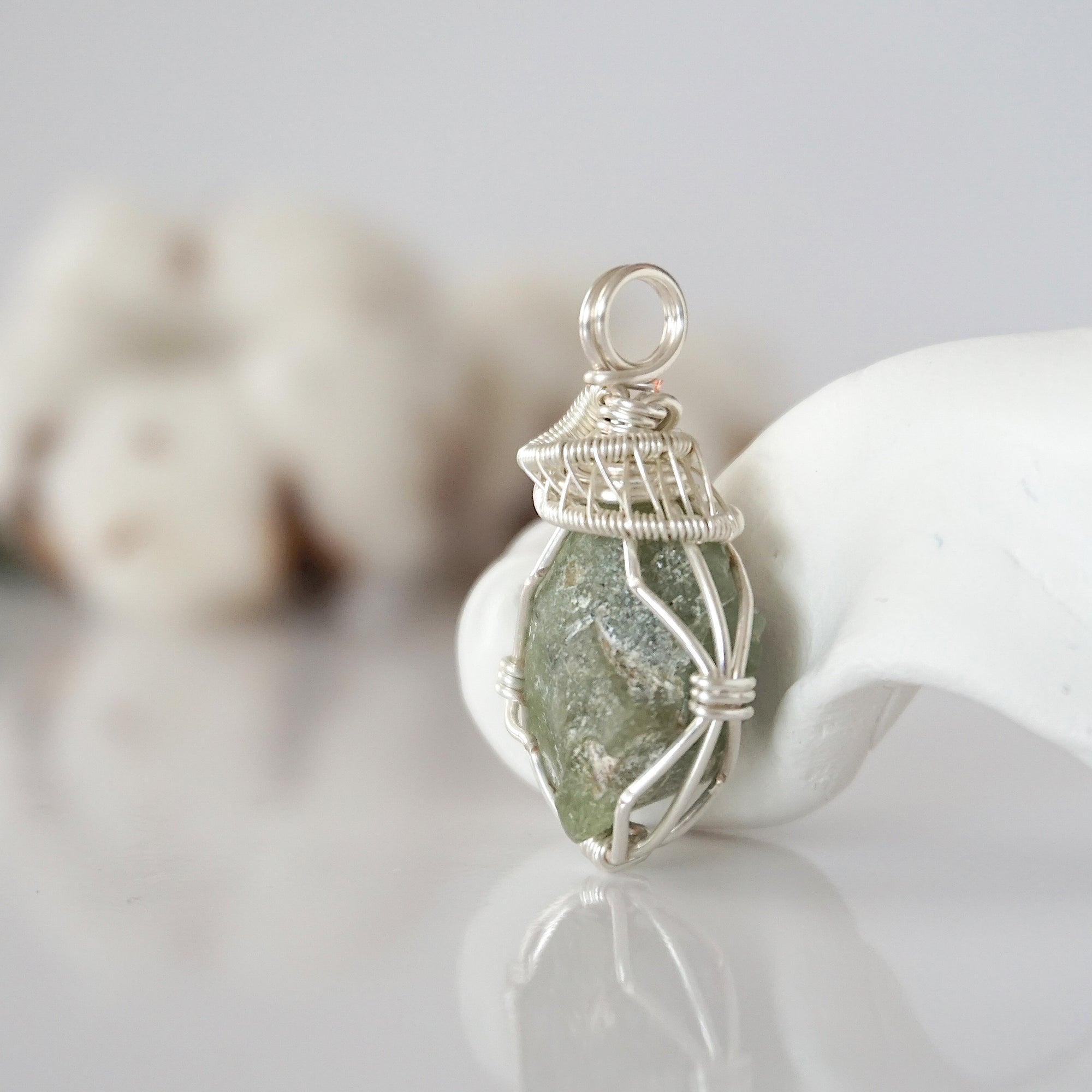 Left side detail of raw peridot crystal pendant — intricate silver finish wire weaving technique, nickel-free wire, handcrafted artisan wire wrapped jewelry, Designs by Nature Gems