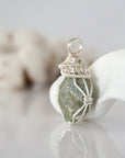Left side detail of raw peridot crystal pendant — intricate silver finish wire weaving technique, nickel-free wire, handcrafted artisan wire wrapped jewelry, Designs by Nature Gems