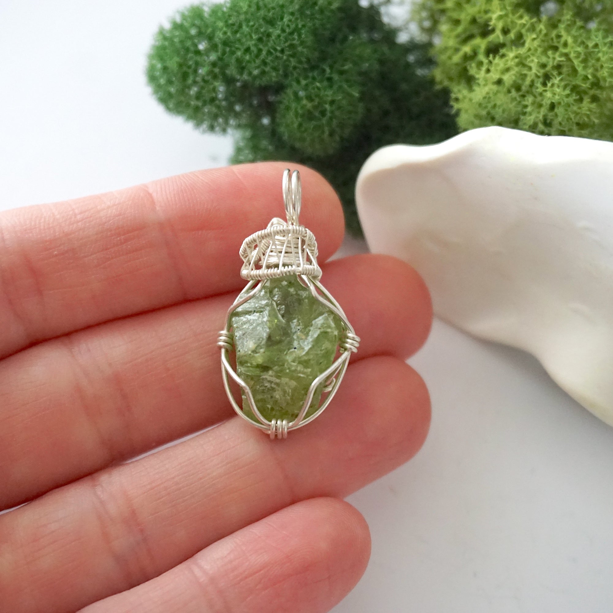 Handmade raw peridot pendant held in hand showing size — natural green peridot stone wire wrapped in 925 sterling silver, approx. 1 inch, one of a kind