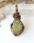 Front view of raw peridot pendant for women — vivid olive green crystal with natural surface texture, antique bronze wire wrap, handcrafted August birthstone jewelry