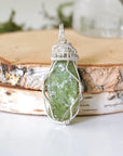 Front view of raw peridot pendant for women — vivid olive green crystal with natural surface texture, 925 sterling silver wire wrap, handcrafted August birthstone jewelry