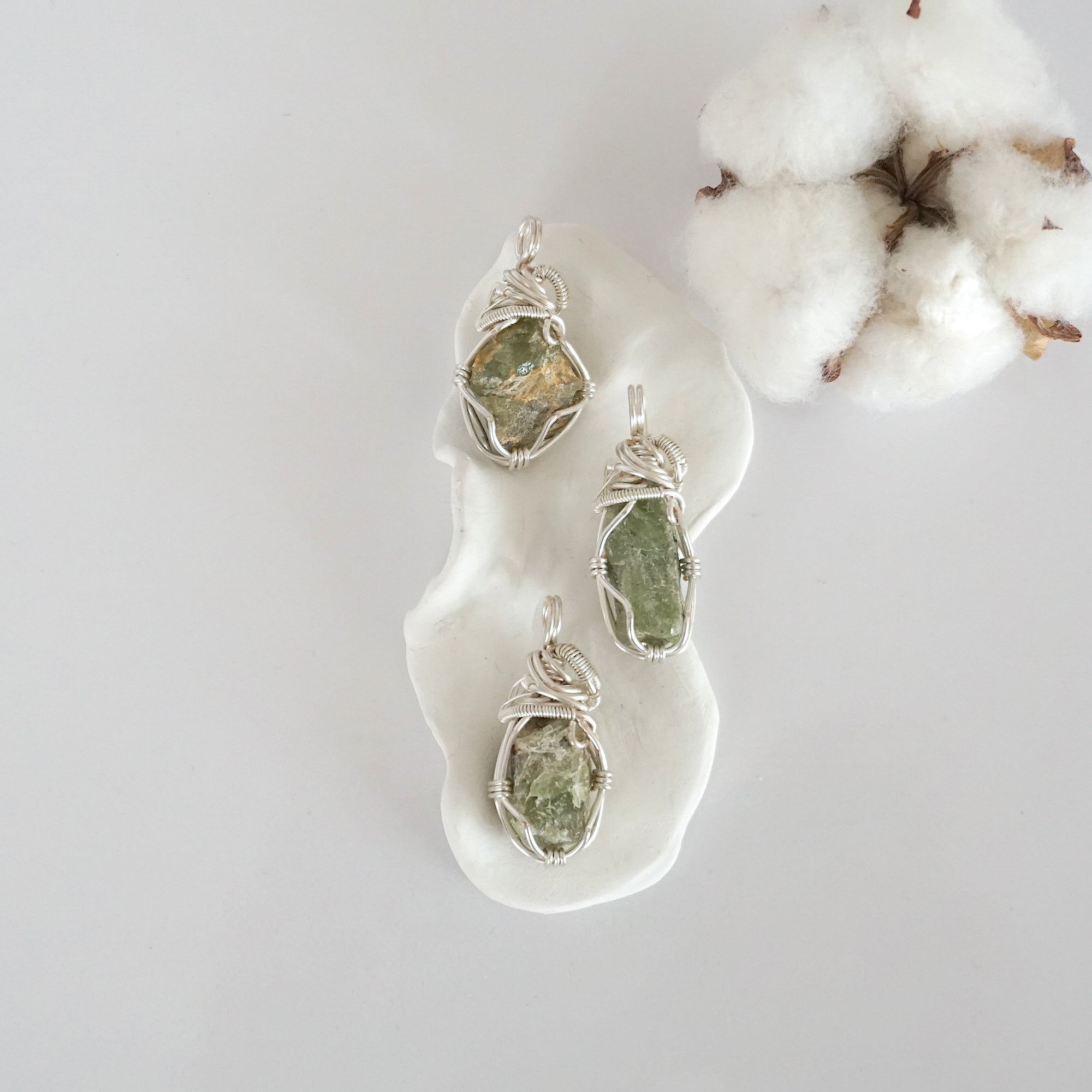 Three raw peridot pendants showing natural variation in stone size, shape, and green colour — each one of a kind, August birthstone, silver wire wrapped, Designs by Nature Gems