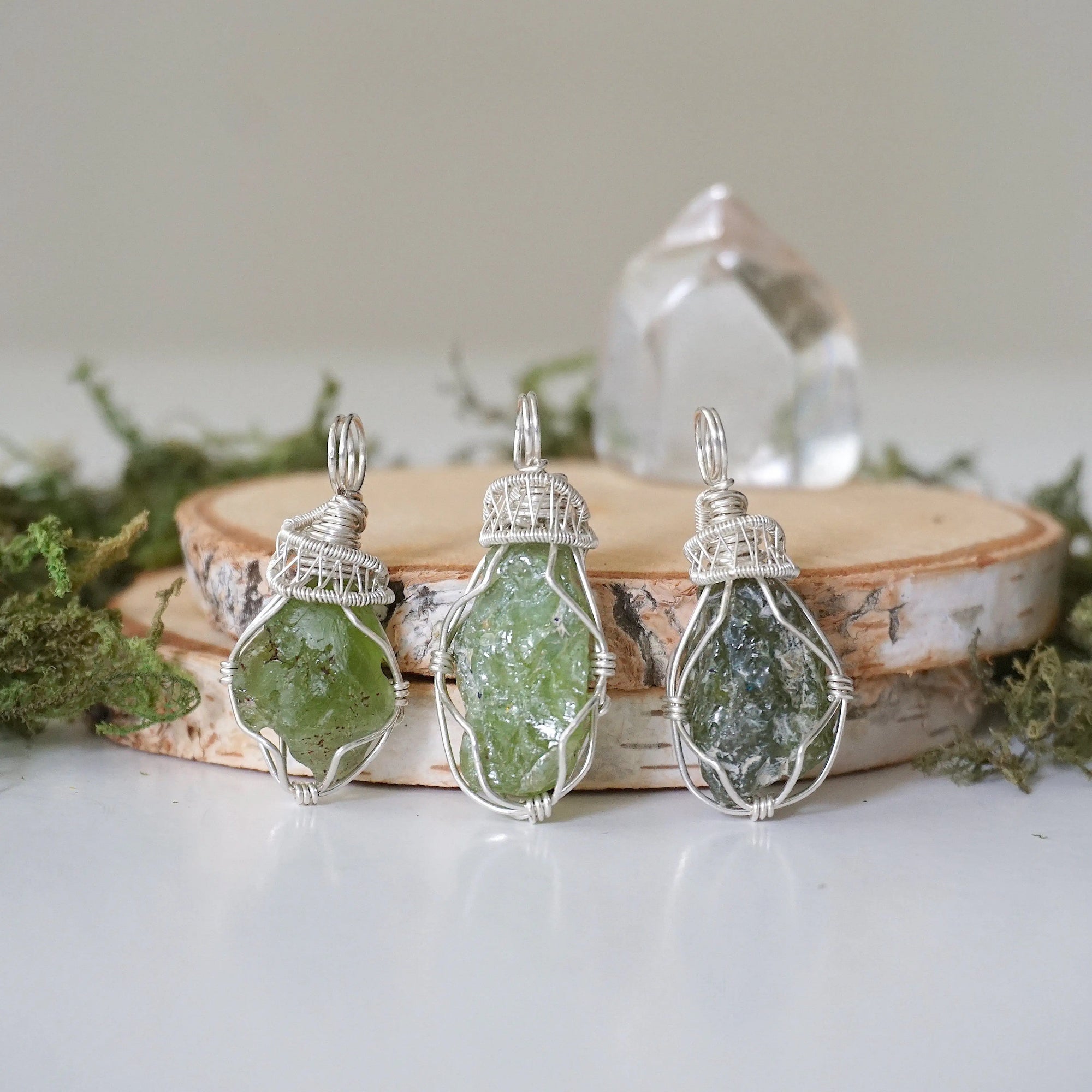 Three raw peridot pendants for women showing natural variation in size, shape, and olive green colour — handcrafted 925 sterling silver wire wrapped August birthstone necklaces