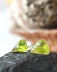 Front view of raw peridot stud earrings — vivid translucent olive green natural crystal on sterling silver posts, dainty handcrafted August birthstone earrings by Designs by Nature Gems