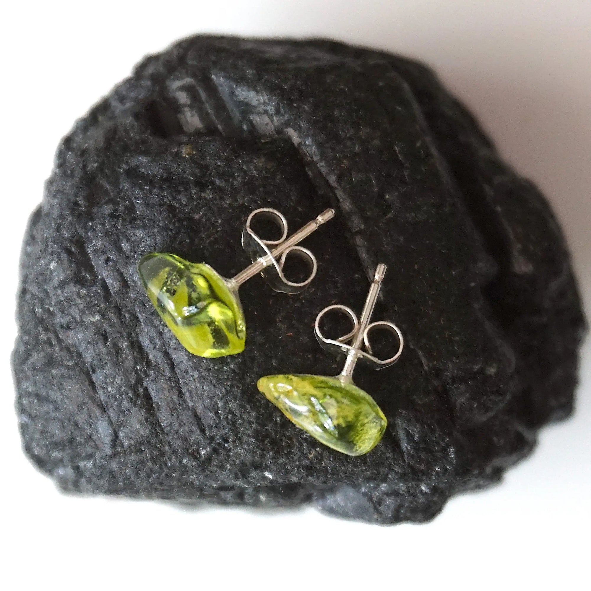 Top angle view of raw peridot stud earrings showing natural stone surface and light-catching translucency — 925 sterling silver stud earrings, August birthstone crystal jewelry