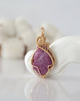 Detailed front view of raw pink ruby pendant in 14k gold filled. Unique wire wrapped July birthstone jewelry by Designs by Nature Gems.