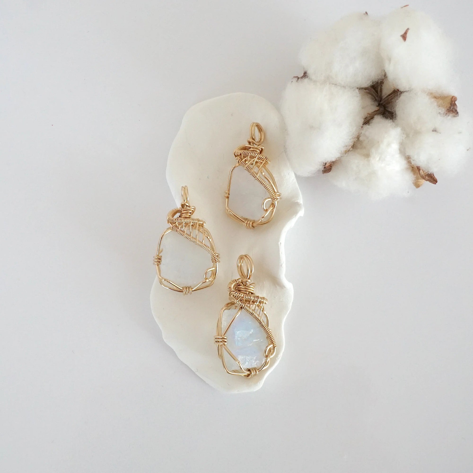 Three raw rainbow moonstone pendants in 14k gold filled, showing natural variation in size, shape, and color. Handcrafted June birthstone jewelry by Designs by Nature Gems.