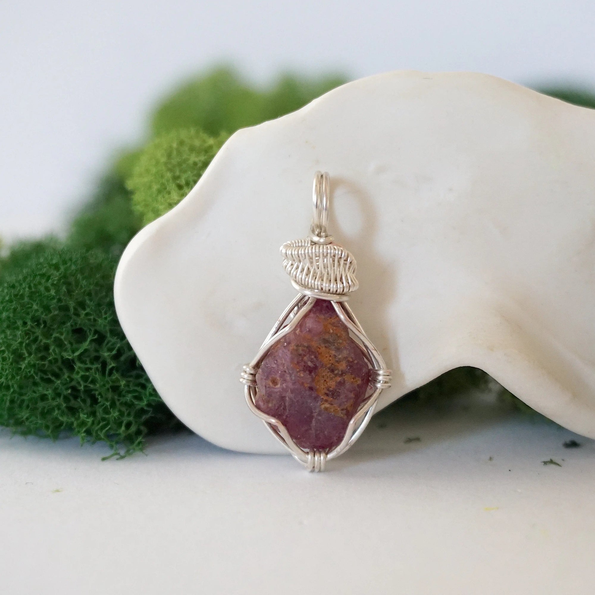 Front view of a natural raw ruby pendant hand-wrapped in soft silver finish over copper wire — July birthstone necklace for women