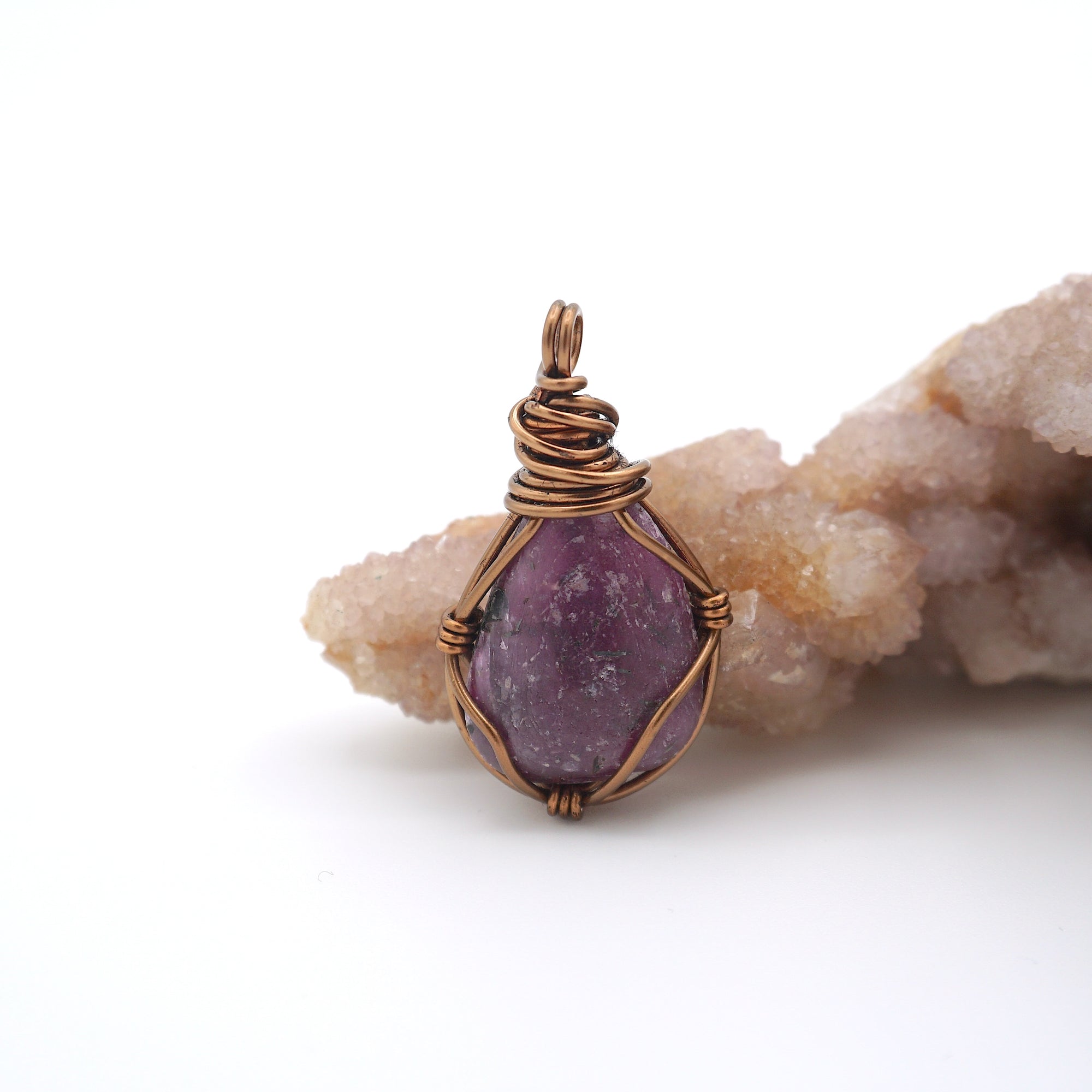 Front view of a natural polished-raw ruby pendant hand-wrapped in antique bronze copper wire — July birthstone necklace