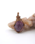 Front view of a natural polished-raw ruby pendant hand-wrapped in antique bronze copper wire — July birthstone necklace