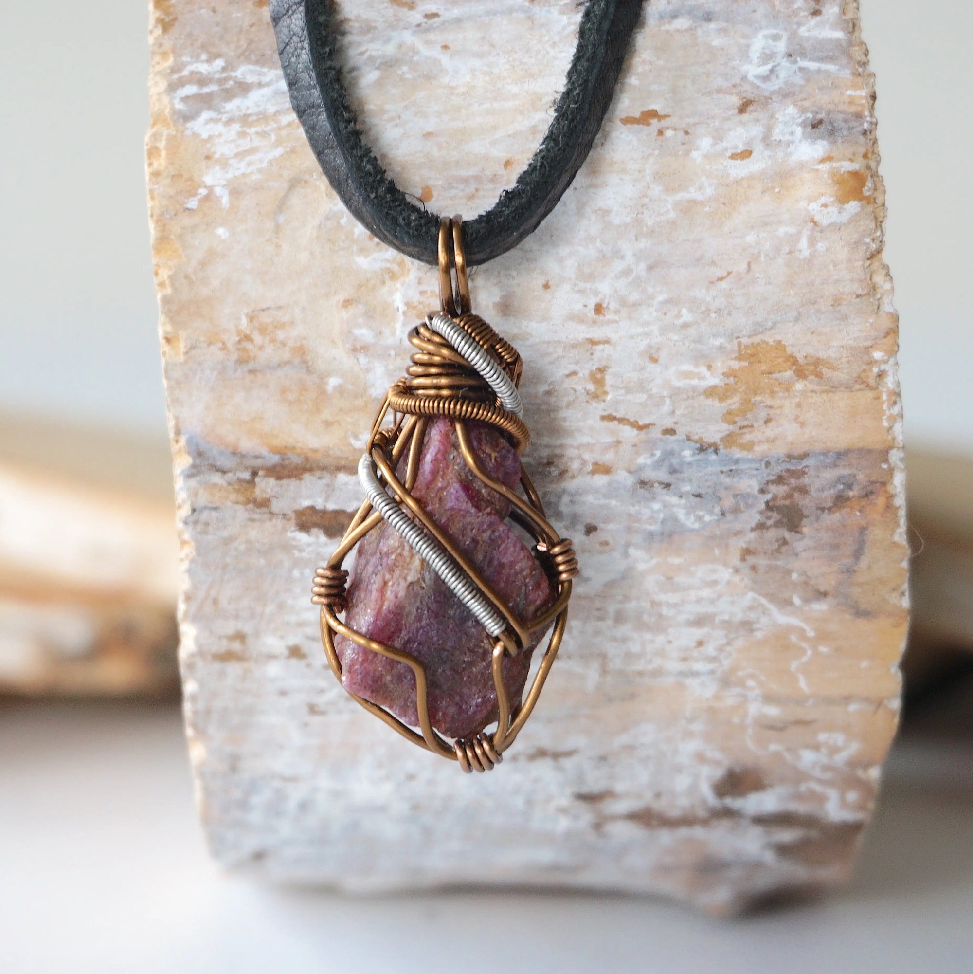 Back angle of men's raw ruby pendant displaying bronze and dark silver wire wrapping craftsmanship — handmade artisan crystal jewelry, nickel-free