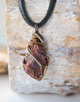Back angle of men's raw ruby pendant displaying bronze and dark silver wire wrapping craftsmanship — handmade artisan crystal jewelry, nickel-free
