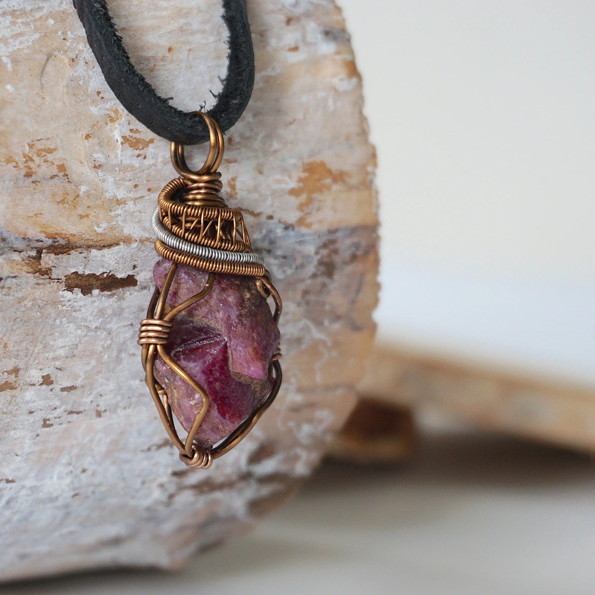 Right side view of men's handcrafted raw ruby pendant showing two-tone bronze and dark silver artisan wire wrapping detail