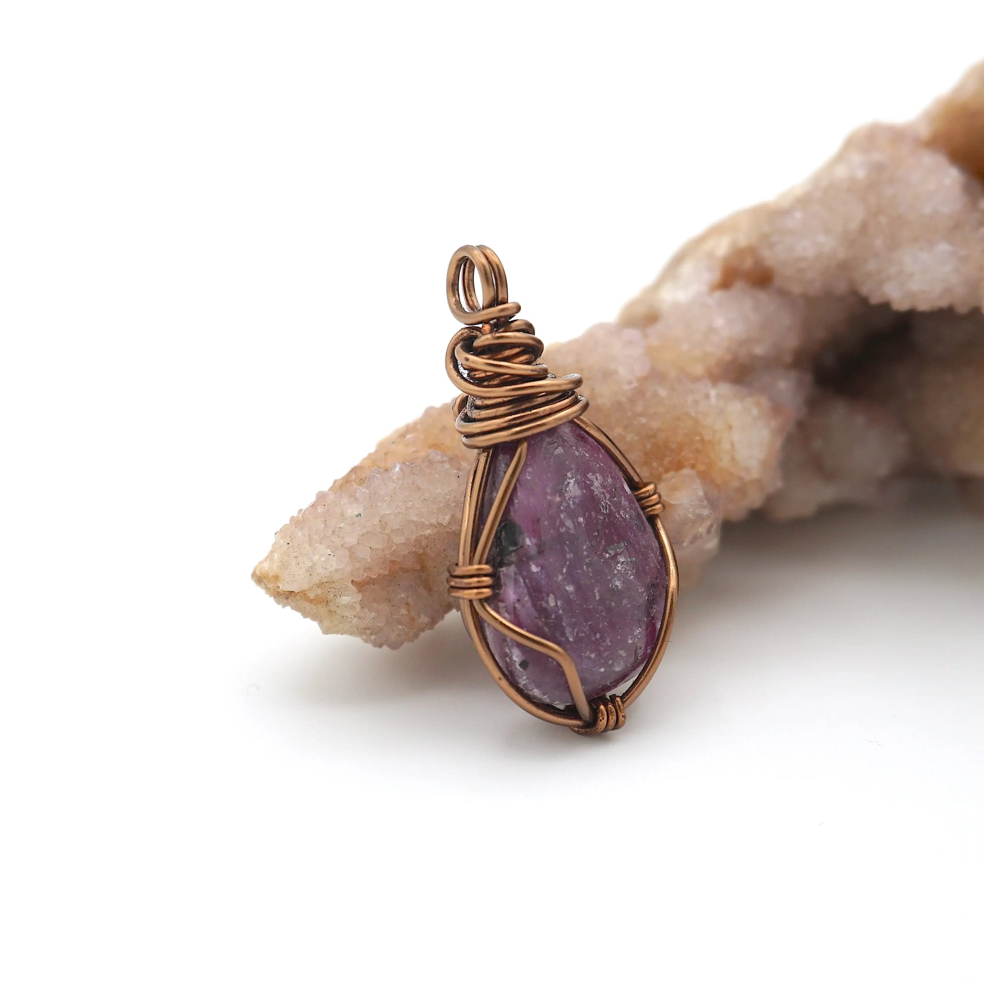 Side view of handcrafted raw ruby pendant showing artisan wire wrapping detail in antique bronze finish over copper